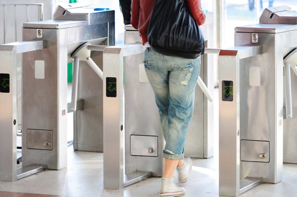 Woman In Rolled Up Denim Jeans Entering A Theme Park Through A Waist High Turnstile.